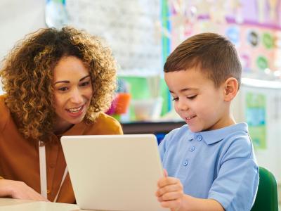 A woman and child smile and look at a tablet